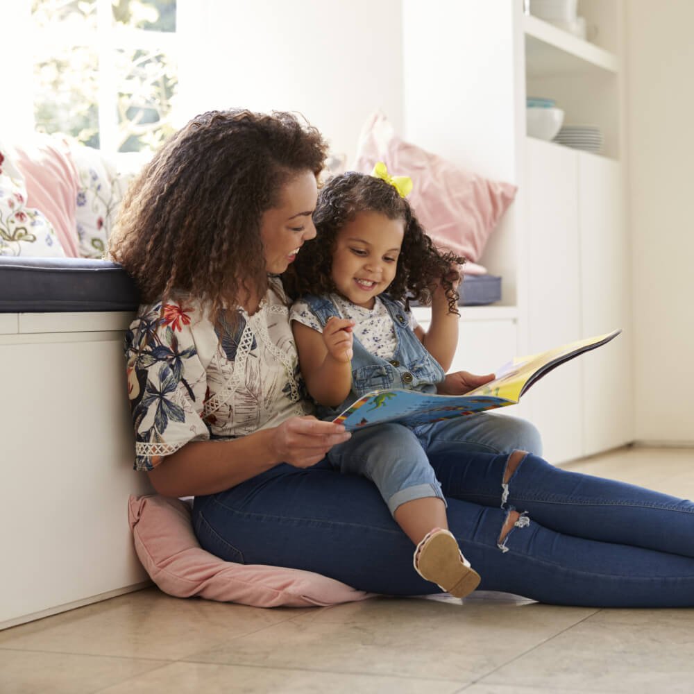 Mom and daughter reading by window