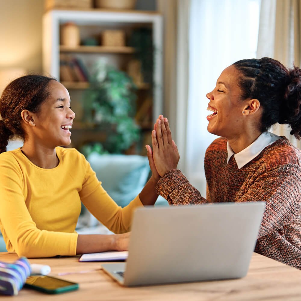 Mom and daughter high five after successful online reading lesson