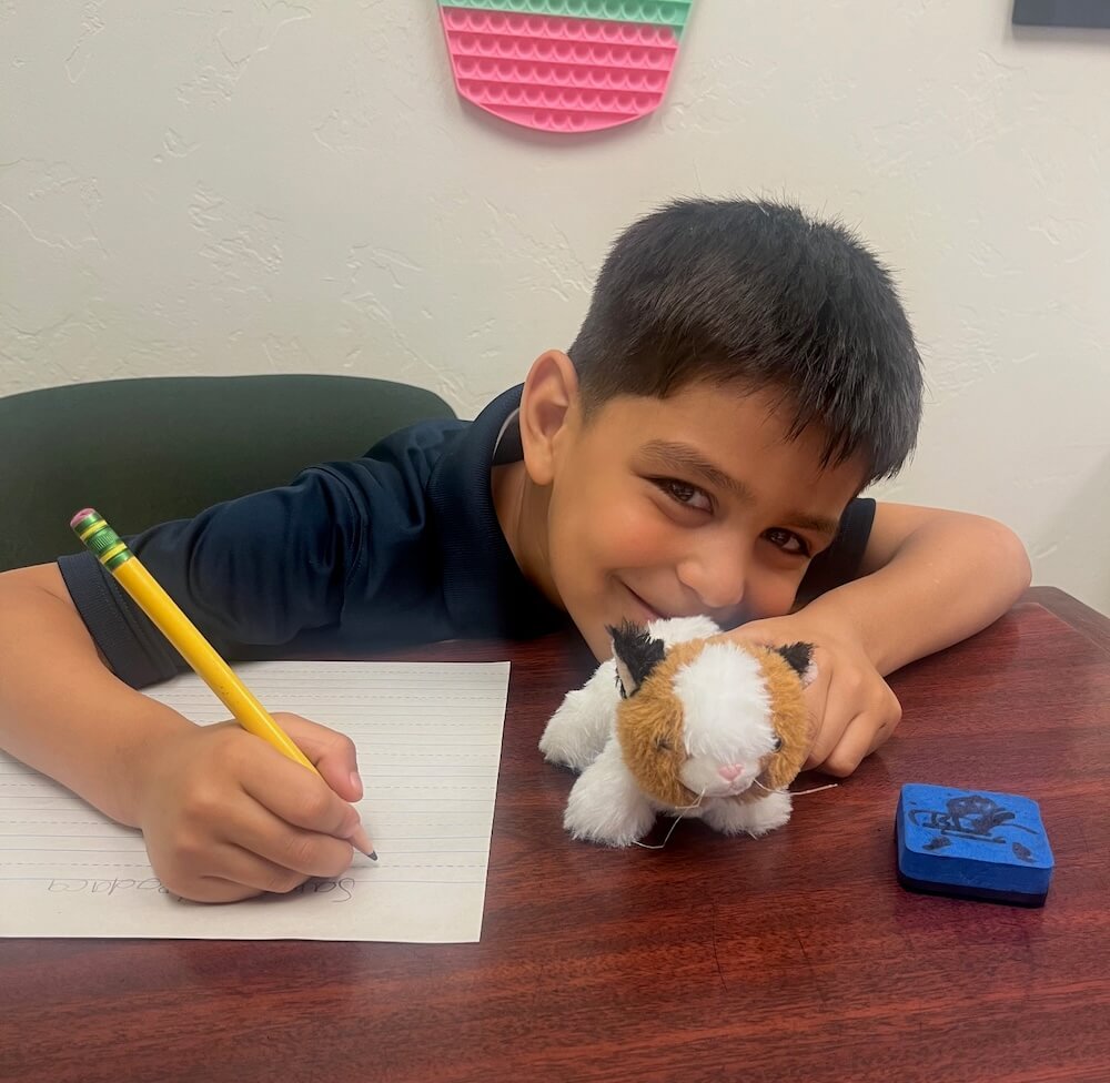 Kindergartner with stuffed animal writing