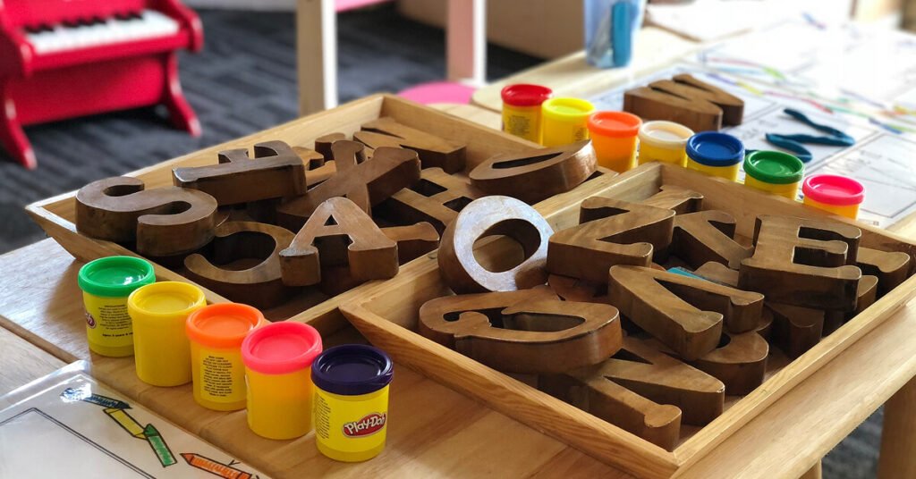 Preschool classroom with playdoh and wooden letters on table