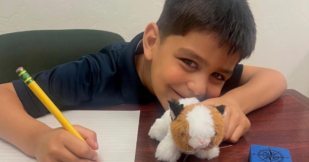 Tutoring student writing with pencil and holding stuffy