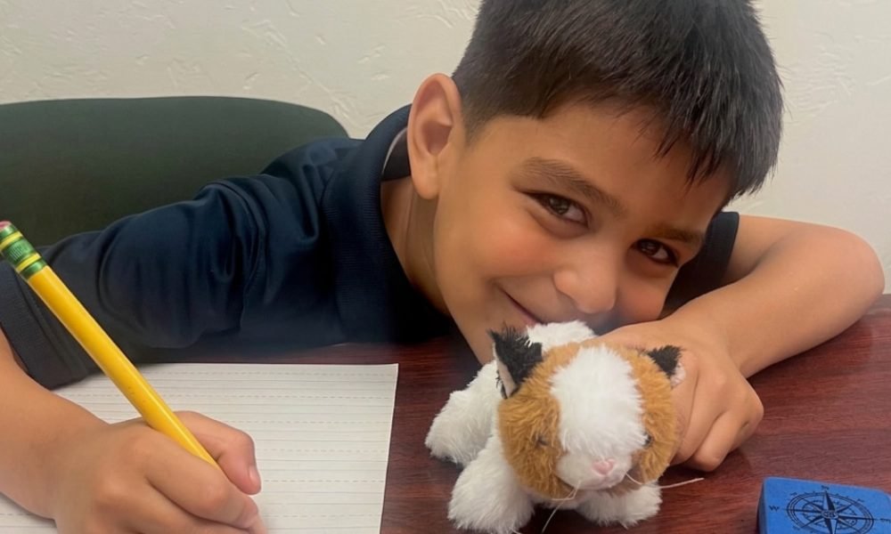 Tutoring student writing with pencil and holding stuffy
